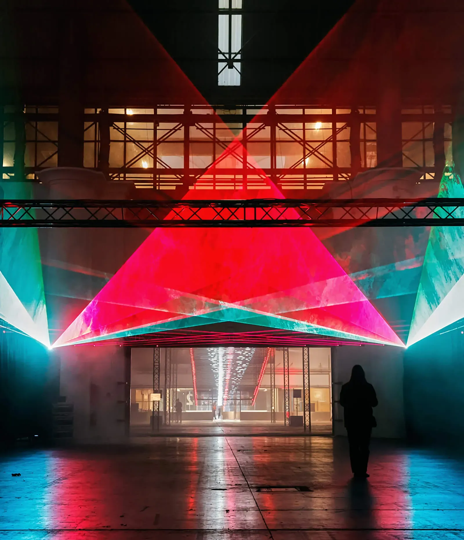 Red, pink and turquoise light beams inside a festival venue